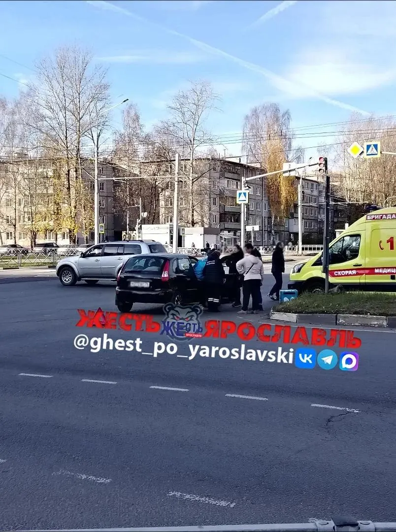 На месте происшествия работают скорая помощь и полиция; на дороге лежат электросамокат и рюкзак доставки.